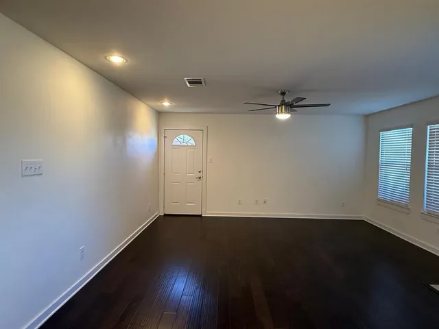 an empty room with wooden floor and windows