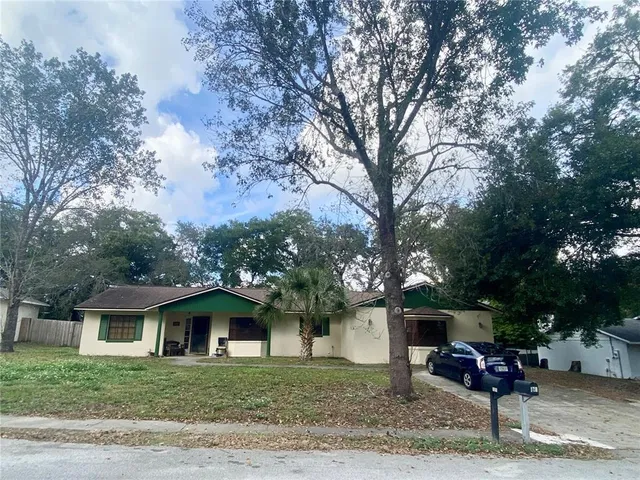 a front view of a house with garden and trees
