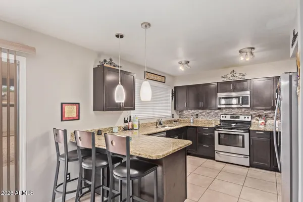 a kitchen with stainless steel appliances granite countertop a stove top oven a sink dishwasher and a refrigerator