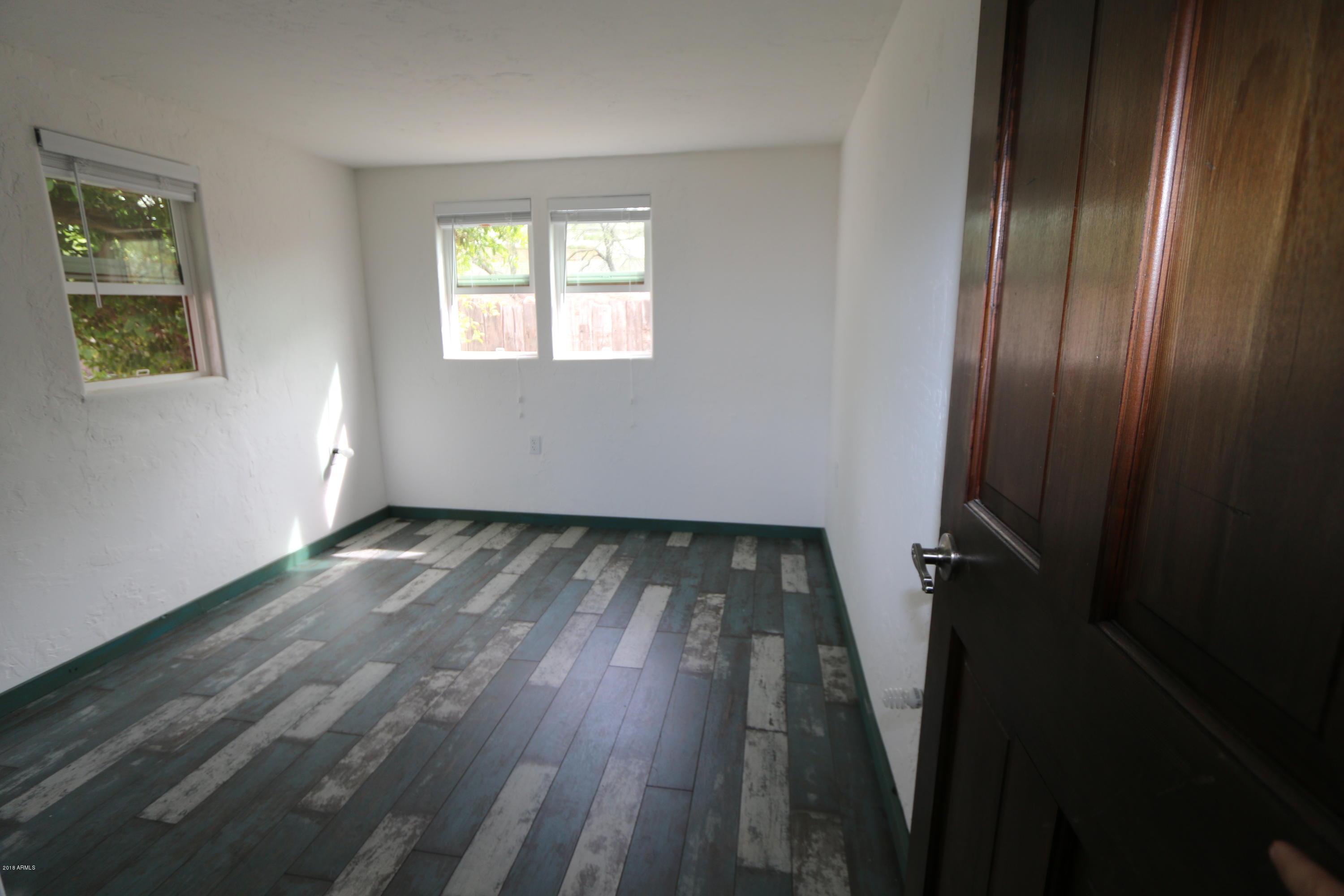 1730 East Lehi Road, Unit 2 Mesa, AZ 85203 - Photo 9 of 13 an empty room with wooden floor and windows
