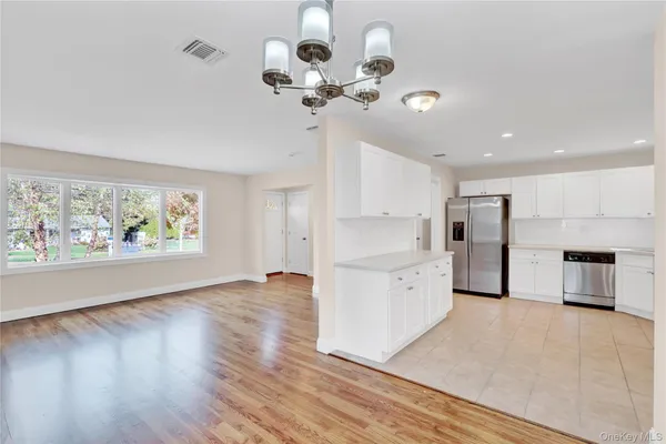 a large kitchen with white cabinets a stove a microwave and a hard wood floor