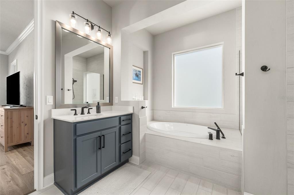 10778 Southwest 34th Road Gainesville, FL 32608 - Photo 21 of 62 a bathroom with a tub sink double vanity granite tub shower and mirror