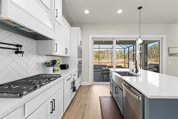 a kitchen with kitchen island a sink a stove a refrigerator and white cabinets with wooden floor