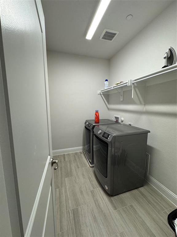 7849 Sunset Boulevard Rowlett, TX 75088 - Photo 14 of 19 The property features a dedicated laundry area with tile flooring, a horizontal light fixture, and white wall shelving