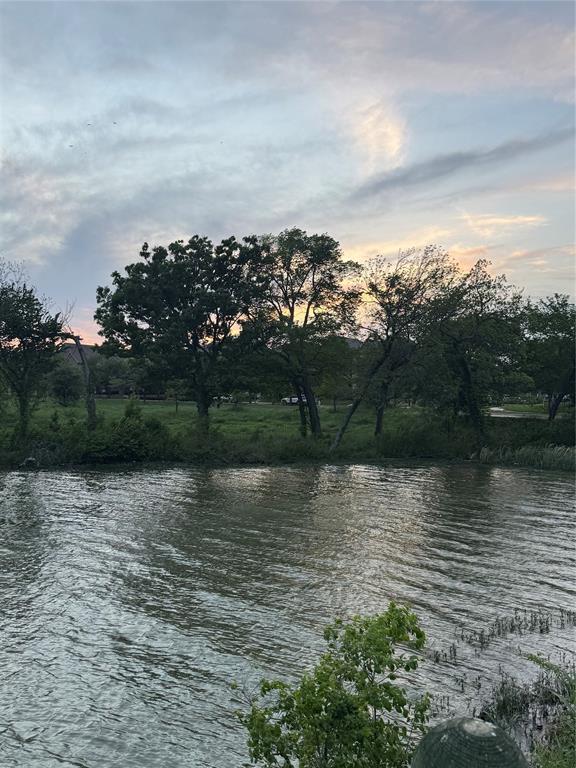 7849 Sunset Boulevard Rowlett, TX 75088 - Photo 18 of 19 Scenic water view with lush green trees lining the banks, set against a backdrop of a soft, cloudy sky