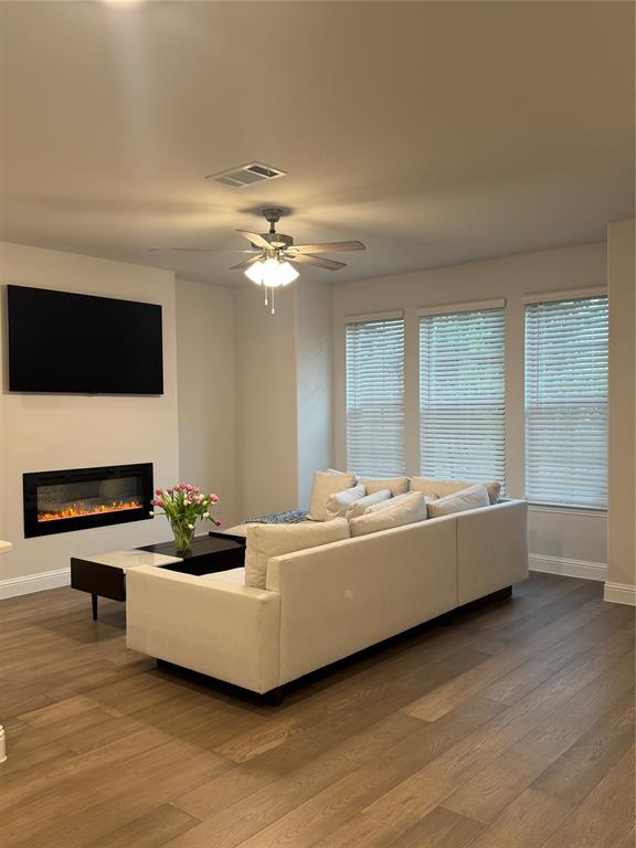 7849 Sunset Boulevard Rowlett, TX 75088 - Photo 3 of 19 This living area features wood flooring, a ceiling fan with integrated lighting, and several windows fitted with blinds