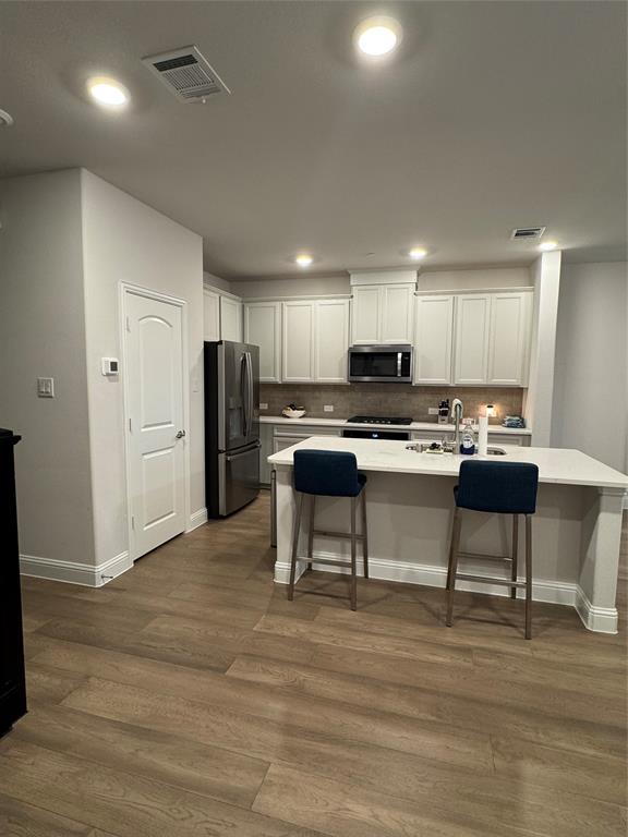 7849 Sunset Boulevard Rowlett, TX 75088 - Photo 6 of 19 The kitchen features white cabinetry, stainless steel appliances, and a central island with a light-colored countertop
