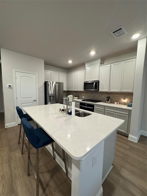 7849 Sunset Boulevard Rowlett, TX 75088 - Photo 7 of 19 The kitchen features a spacious island with a light-colored countertop and an integrated sink, complemented by light-toned cabinetry and stainless steel appliances