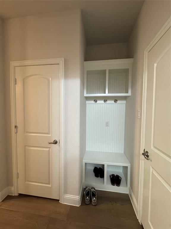 7849 Sunset Boulevard Rowlett, TX 75088 - Photo 9 of 19 The property features a built-in white storage unit with a bench, coat hooks, and upper open shelving, providing practical organization