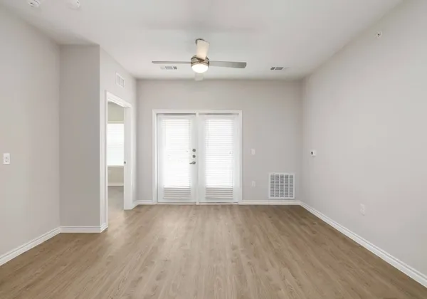 an empty room with wooden floor and windows