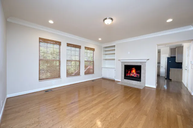a view of an empty room with a window and a kitchen