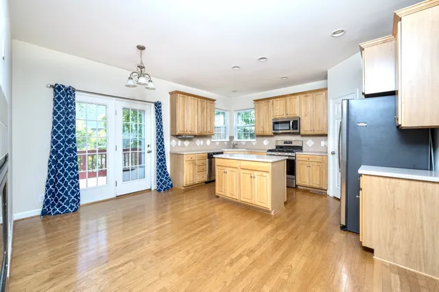 a kitchen with a refrigerator a stove a sink and dishwasher with wooden floor