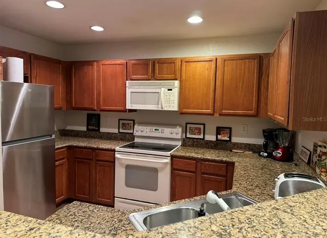 a kitchen with stainless steel appliances granite countertop a sink stove refrigerator and cabinets