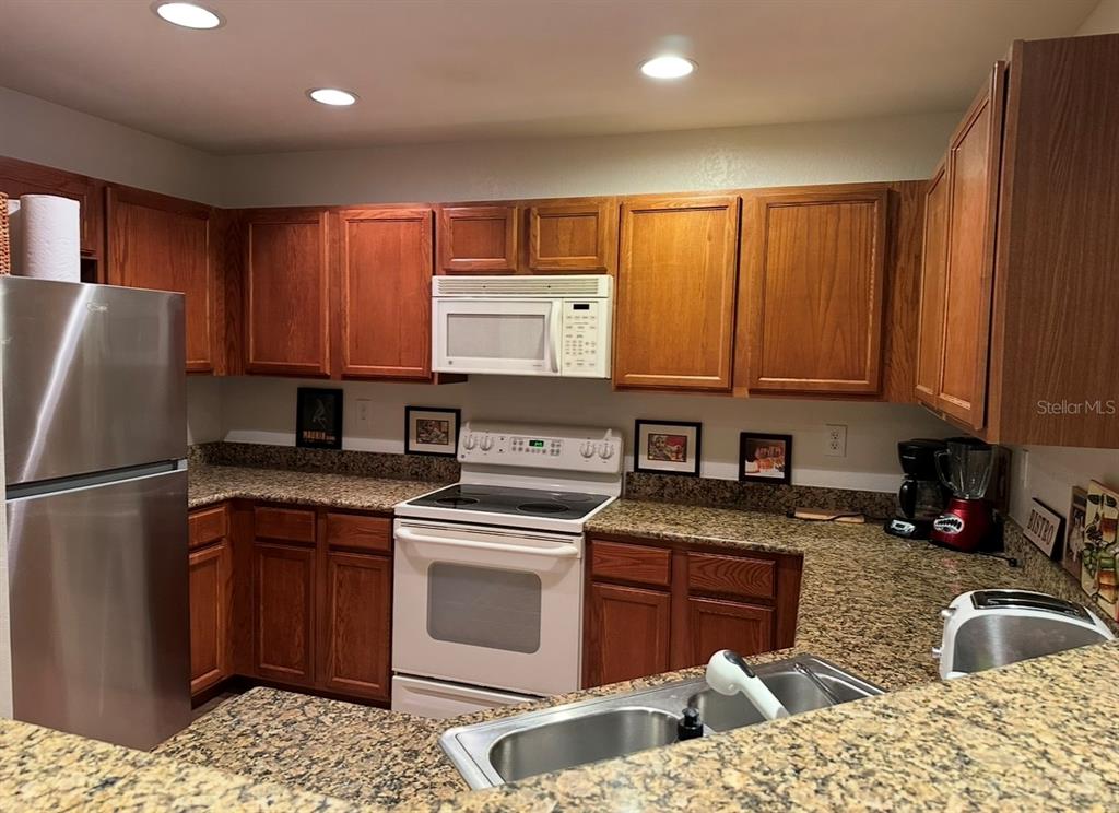 4600 East Moody Boulevard, Unit 3J Bunnell, FL 32110 - Photo 4 of 20 a kitchen with stainless steel appliances granite countertop a sink stove refrigerator and cabinets