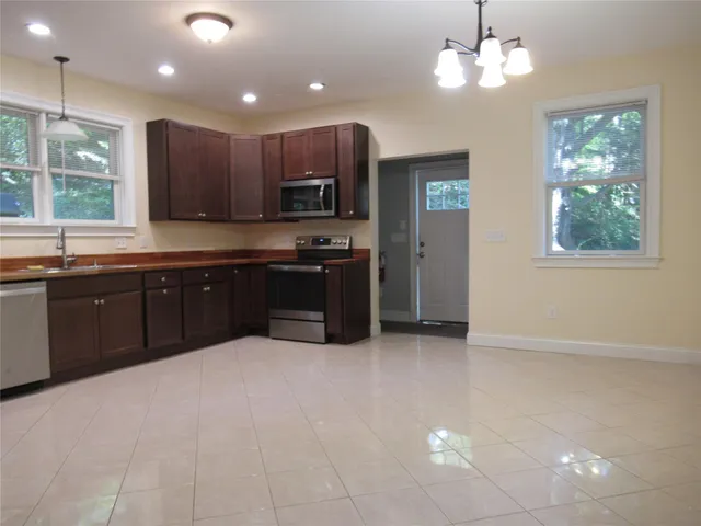 a large kitchen with cabinets a sink and stainless steel appliances