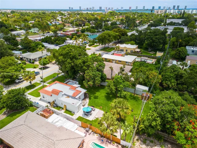 an aerial view of residential houses with outdoor space and trees all around