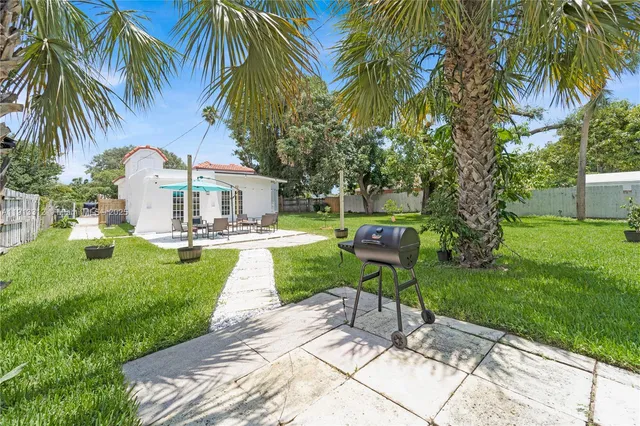 a view of a house with a yard and palm trees