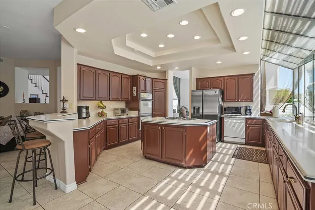 a kitchen with stainless steel appliances kitchen island granite countertop a sink counter space cabinets and a large window