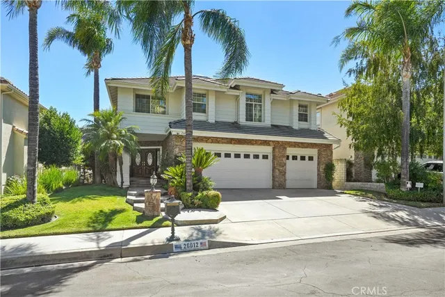 a front view of a house with a garden and palm trees