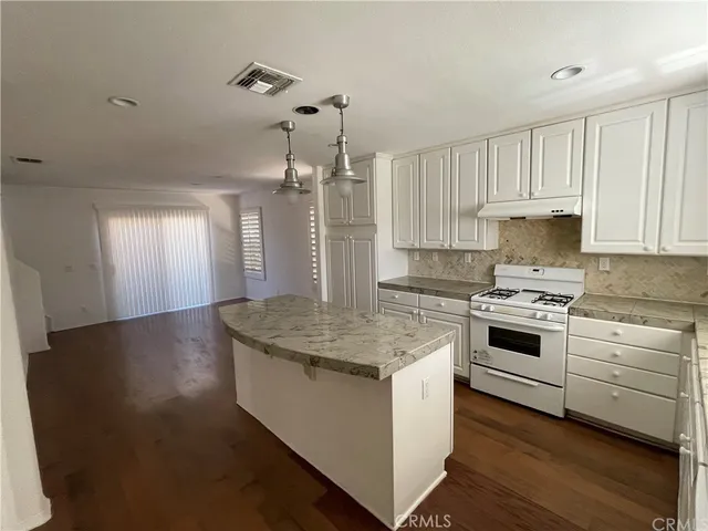 a kitchen that has a sink a stove and wooden floor