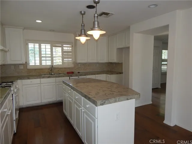 a kitchen with a sink dishwasher a stove a dining table and chairs