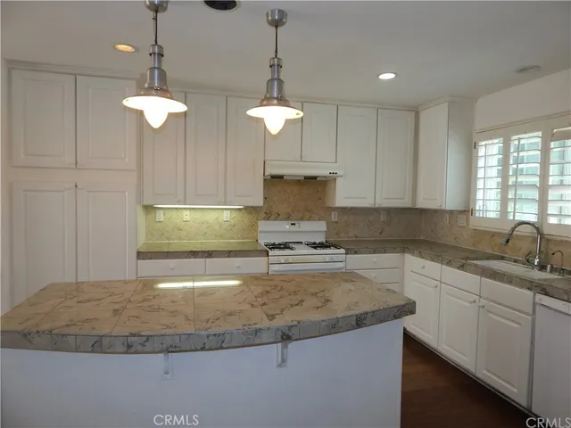a kitchen with stainless steel appliances granite countertop a sink a counter top space cabinets and a window