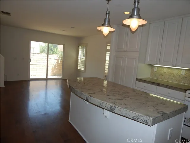 a view of a kitchen island a chandelier and wooden floor