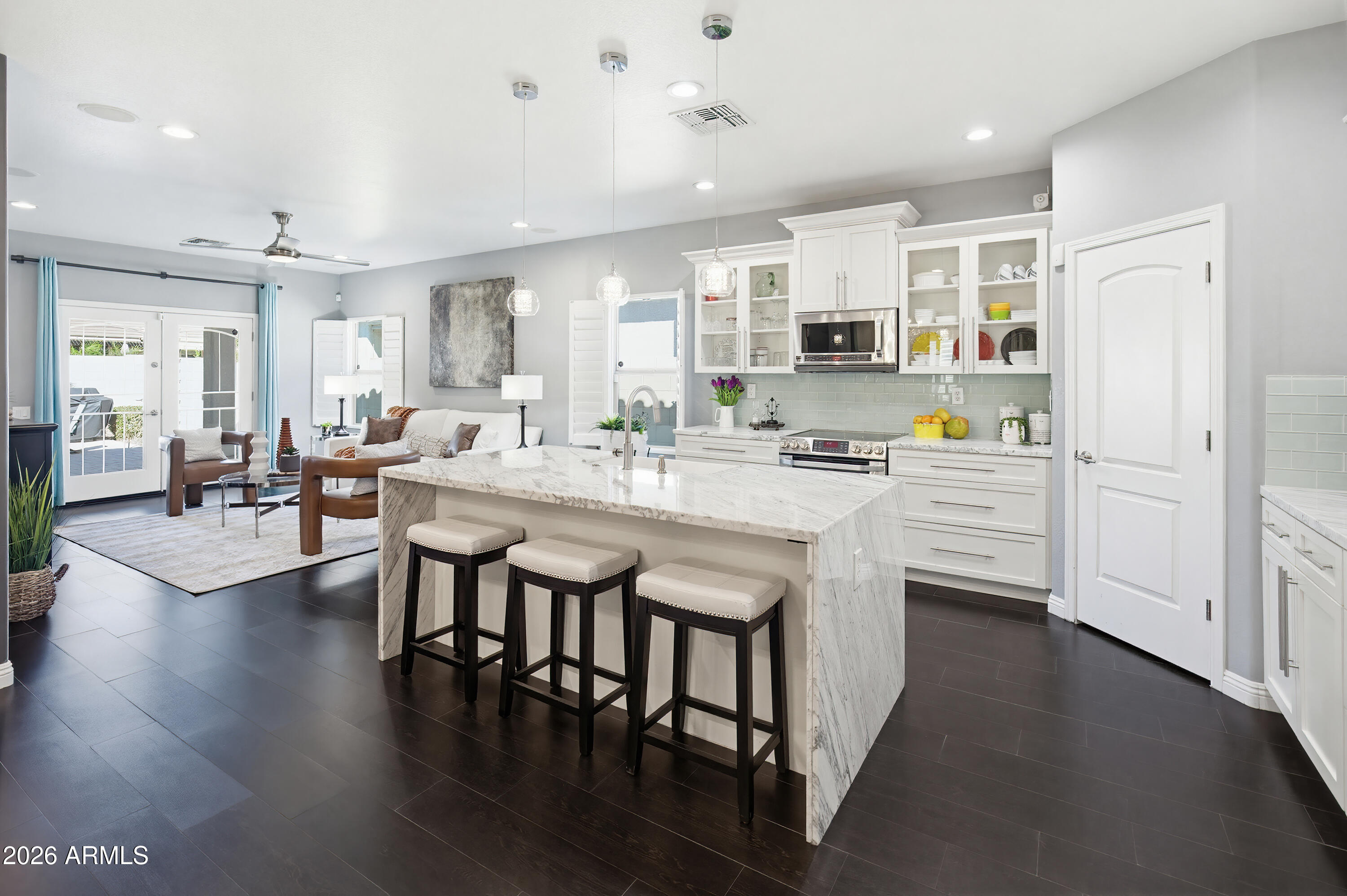 10772 West Yearling Road Peoria, AZ 85383 - Photo 8 of 39 a kitchen with stainless steel appliances kitchen island granite countertop a stove a sink a refrigerator and white cabinets with wooden floor
