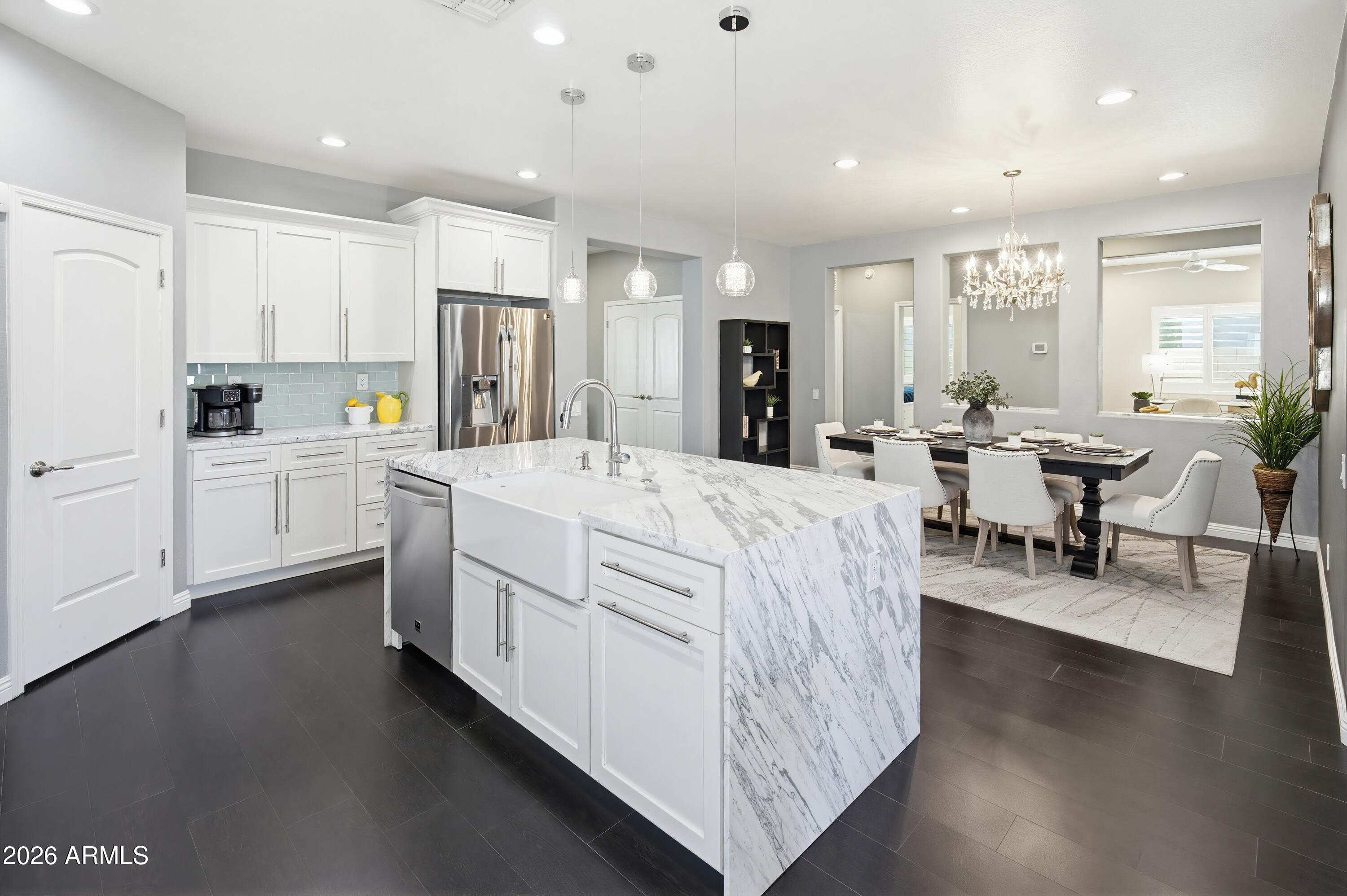 10772 West Yearling Road Peoria, AZ 85383 - Photo 9 of 39 a large white kitchen with kitchen island a stove a sink a dining table and chairs with wooden floor