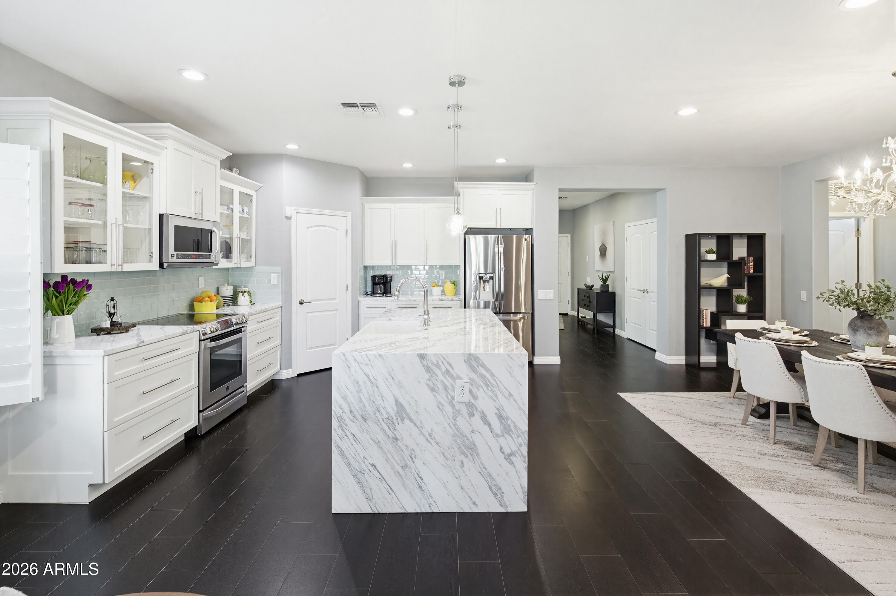 10772 West Yearling Road Peoria, AZ 85383 - Photo 10 of 39 a large open kitchen with stainless steel appliances kitchen island a stove a sink dishwasher and a dining table with wooden floor