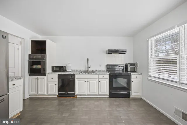 a kitchen with stainless steel appliances granite countertop a stove and white cabinets