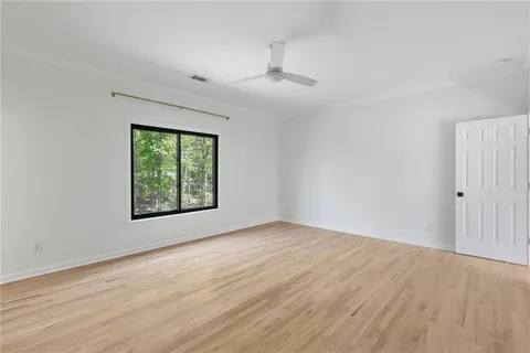 a view of an empty room with window and wooden floor
