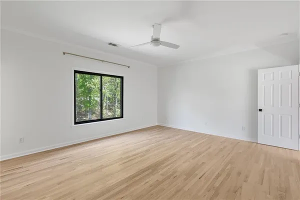 a view of an empty room with window and wooden floor