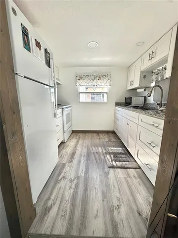 a kitchen with granite countertop white cabinets and white appliances