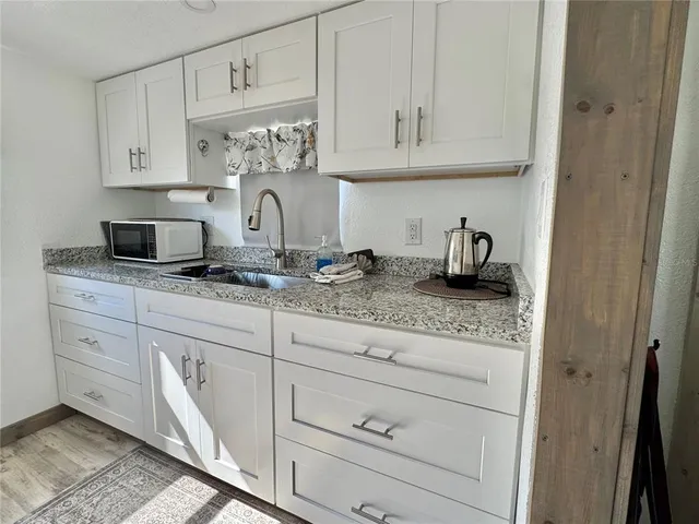 a kitchen with a white cabinets and wooden floor