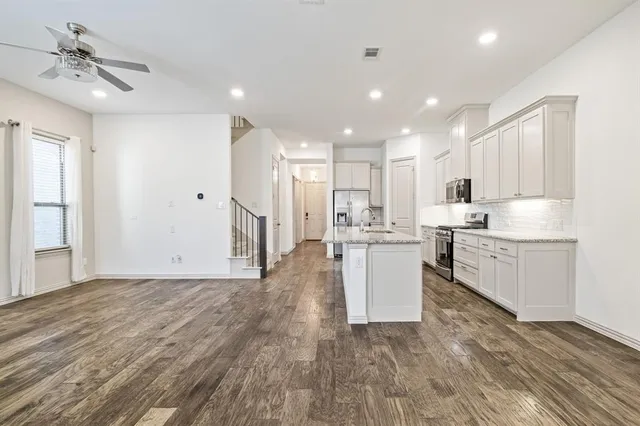 a view of a kitchen with kitchen island a sink stainless steel appliances and cabinets