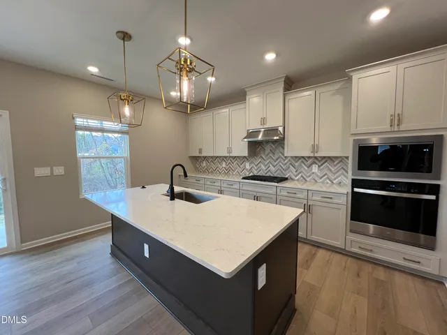 a large kitchen with a center island wooden floor stainless steel appliances and a window