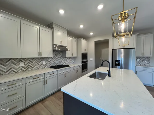 a kitchen with kitchen island granite countertop a sink a counter space stainless steel appliances and cabinets