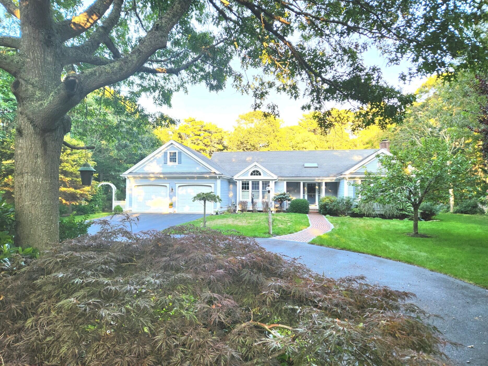 a view of house with a yard and large trees