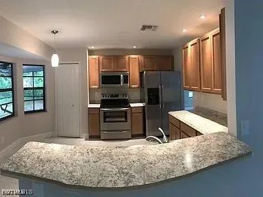 a kitchen with stainless steel appliances granite countertop a refrigerator a stove and a sink with wooden cabinets