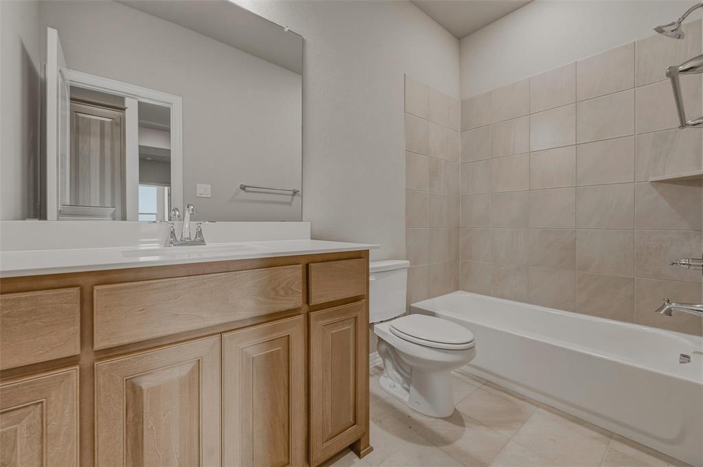 1201 Colca Drive Springtown, TX 76082 - Photo 21 of 32 Bathroom featuring a light wood vanity, white countertop, integrated sink with a chrome faucet, full-width mirror, and a tile shower surround