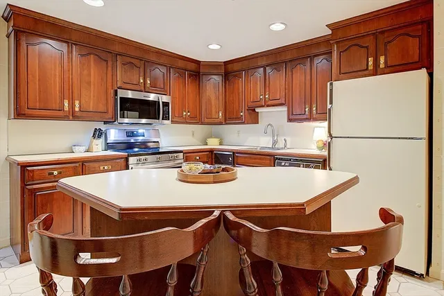 a kitchen with stainless steel appliances granite countertop a sink a microwave refrigerator and chairs