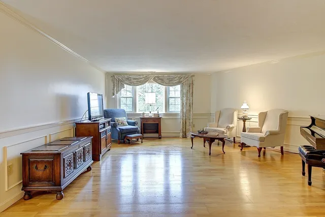 a living room with lots of furniture wooden floor and a large window