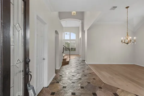 a view of a hallway to a room with wooden floor and a bathroom