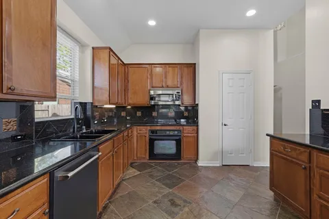 a kitchen with stainless steel appliances granite countertop a stove a sink and a refrigerator