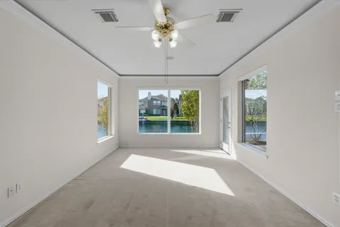 an empty room with a chandelier fan and windows