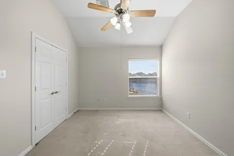 an empty room with a chandelier fan and windows