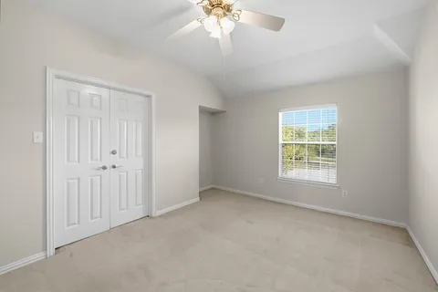 an empty room with a window and a chandelier fan