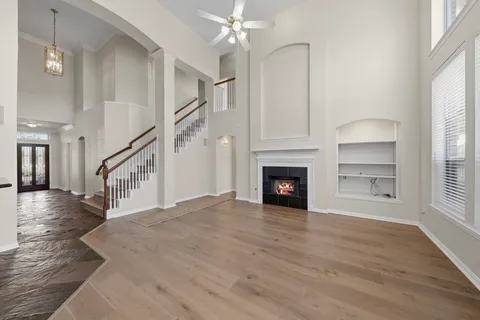 a view of an empty room with wooden floor fireplace and a window