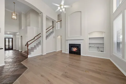 a view of an empty room with wooden floor fireplace and a window